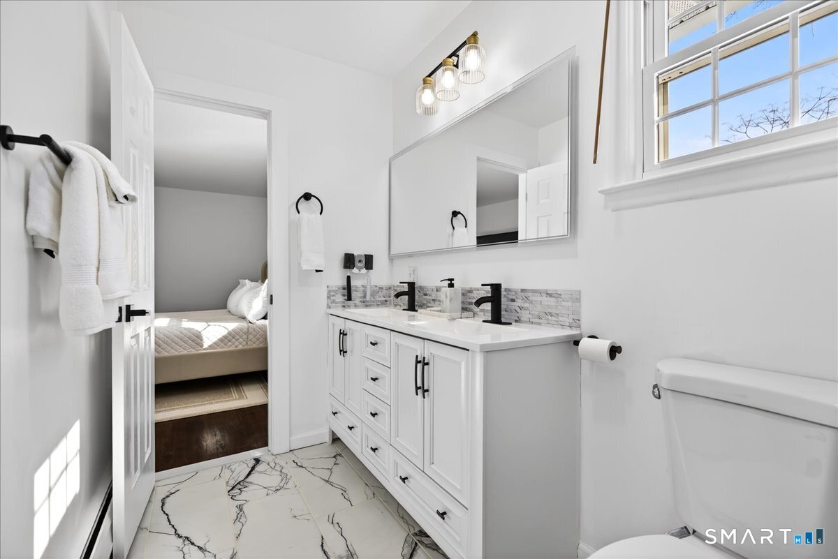 114 Daniel Road Hamden, CT 06517 - Photo 22 of 32 a en suite bathroom with a double vanity sink a mirror a toilet and a shower