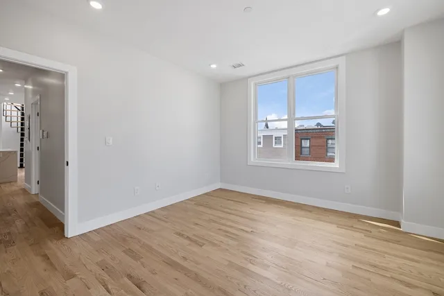 a view of an empty room with window and wooden floor