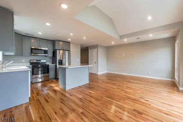 a large kitchen with stainless steel appliances granite countertop a large counter top a stove and a wooden floors