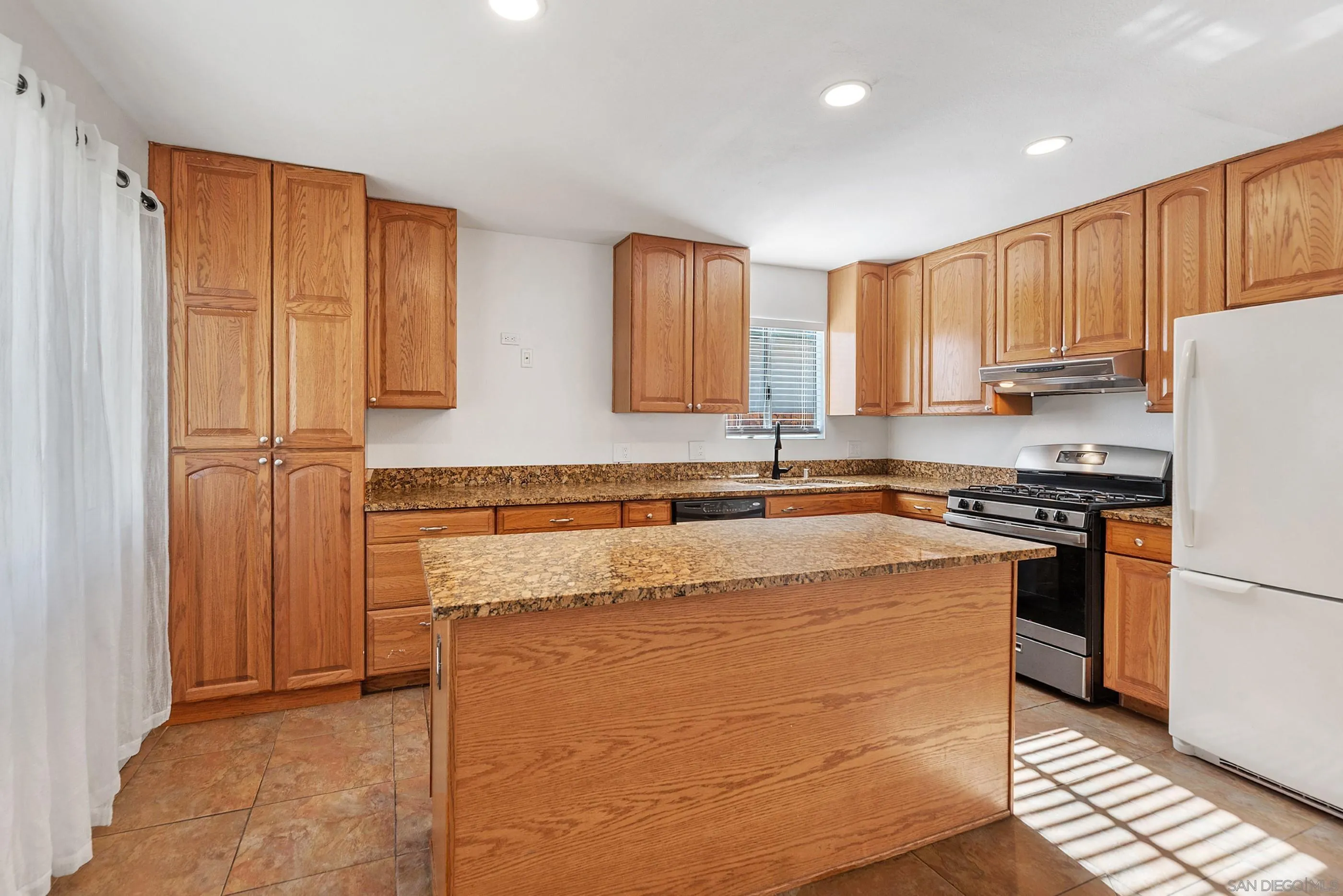 628 Paraiso Avenue Spring Valley, CA 91977 - Photo 9 of 38 a kitchen with stainless steel appliances granite countertop a stove a refrigerator a sink and dishwasher with wooden cabinets