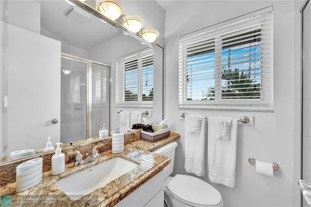 a bathroom with a granite countertop sink mirror vanity and toilet
