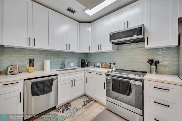 a kitchen with cabinets stainless steel appliances and sink