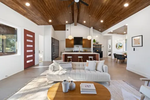 a living room with stainless steel appliances furniture a rug and a kitchen view