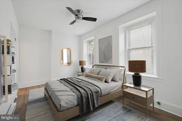 a bedroom with a bed lamp on desk and a window