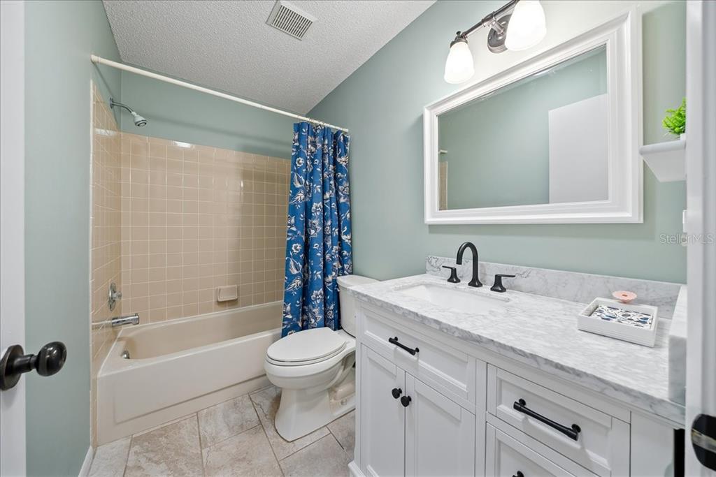 8877 Southwest 96th Street, Unit B Ocala, FL 34481 - Photo 23 of 48 a bathroom with a granite countertop sink a toilet a mirror and shower
