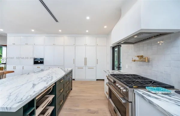 a large kitchen with kitchen island a sink stove and wooden cabinets