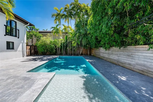 a view of a back yard with plants and large trees