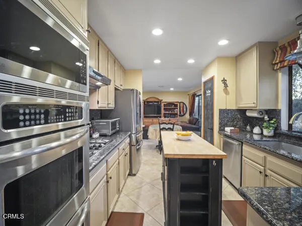 a large kitchen with stainless steel appliances granite countertop a sink and cabinets
