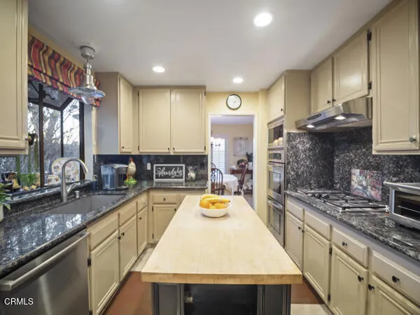 a kitchen with a sink a counter top space stainless steel appliances and cabinets