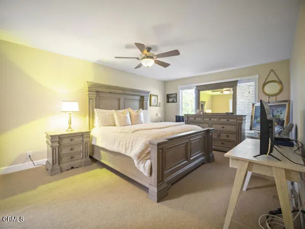 a spacious bedroom with a bed a dresser with wooden floor