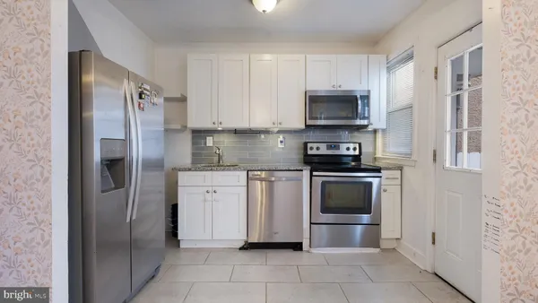 a kitchen with stainless steel appliances granite countertop a refrigerator and a stove top oven