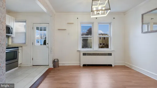 a view of an empty room with kitchen and window