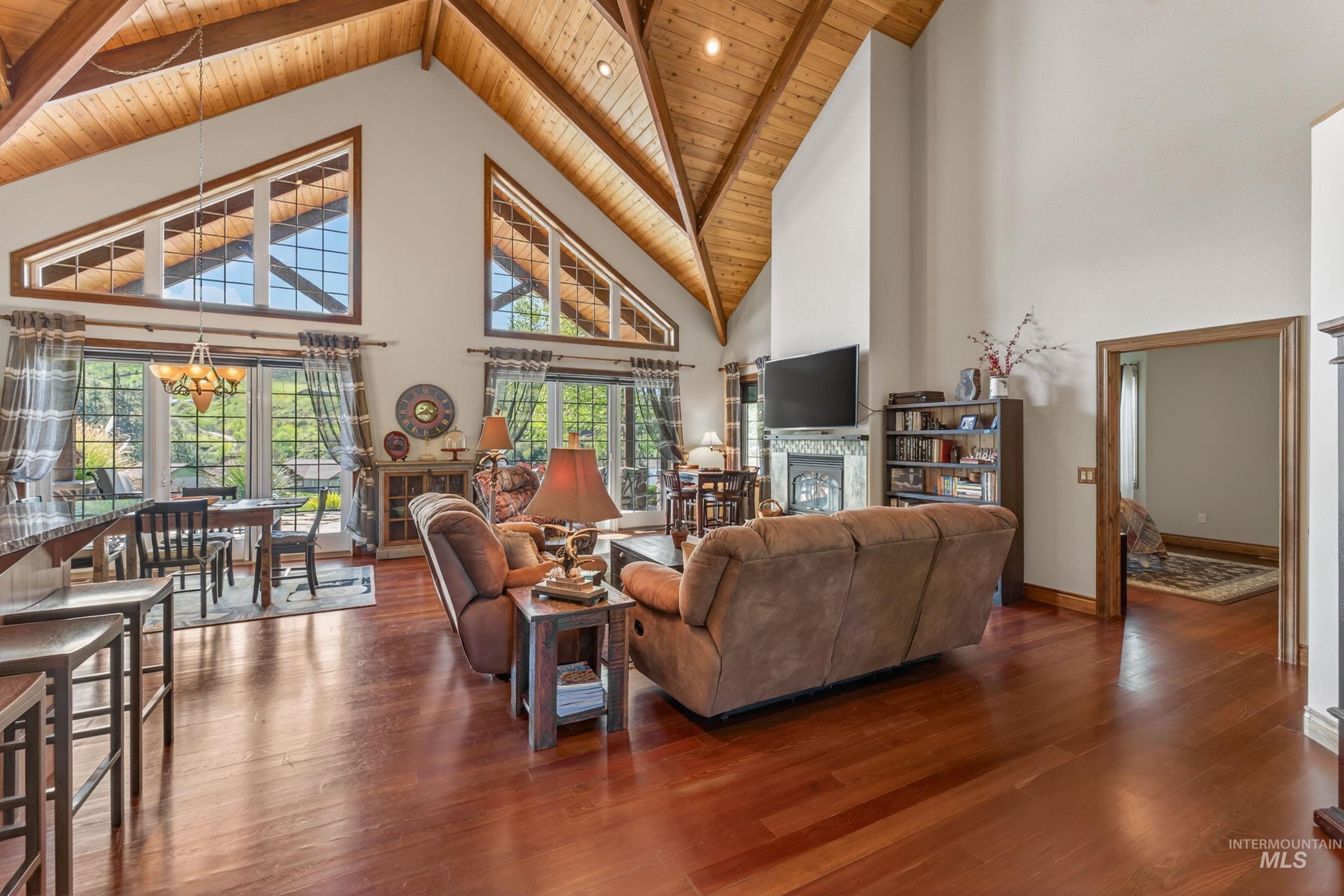 113 Deford Road White Bird, ID 83554 - Photo 17 of 49 Spacious living area featuring a vaulted wood-plank ceiling with exposed beams, rich wood-finish flooring, and a stone-surround fireplace