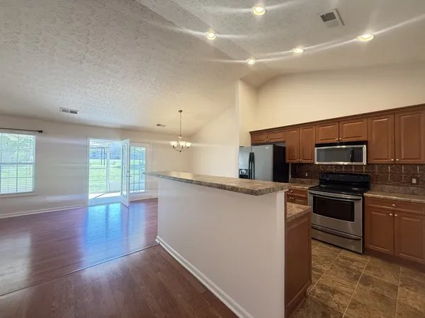 a kitchen with stainless steel appliances granite countertop a refrigerator a sink dishwasher a stove and a microwave oven with wooden floor