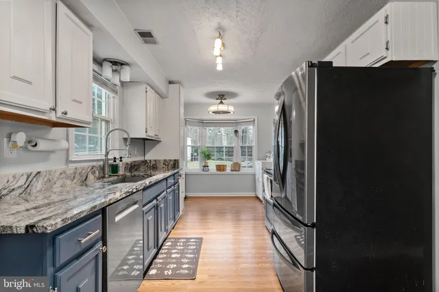 a kitchen with granite countertop a refrigerator and a sink