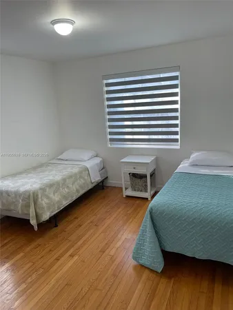 a bedroom with a bed a dresser and wooden floor
