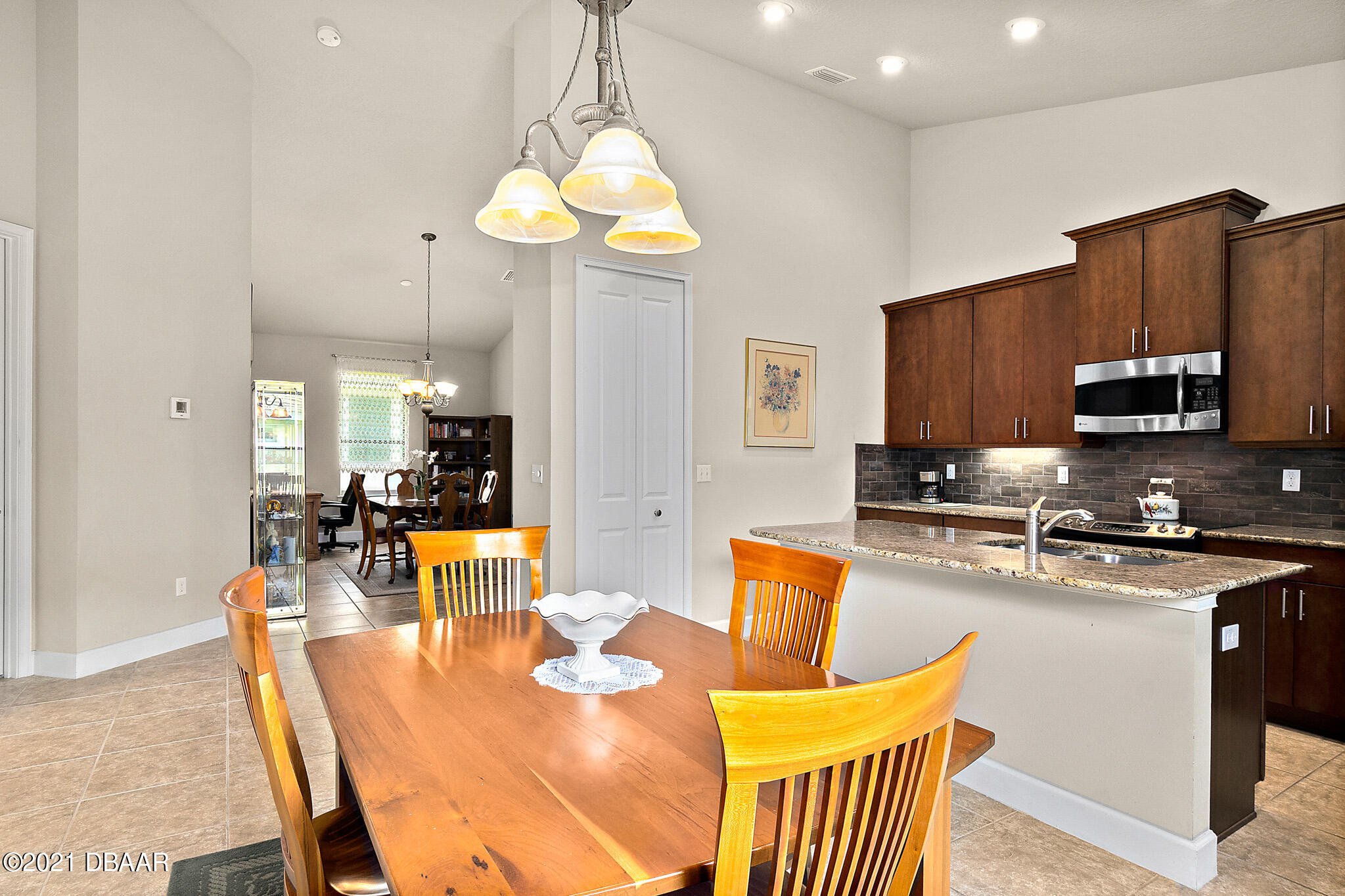 667 Elk River Drive Ormond Beach, FL 32174 - Photo 10 of 49 a kitchen with stainless steel appliances granite countertop a stove a sink a refrigerator a dining table and chairs