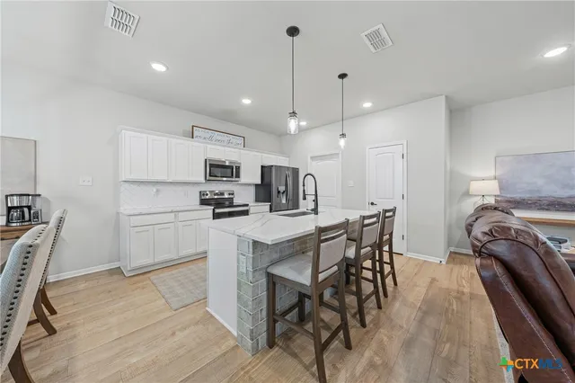 a kitchen with kitchen island granite countertop a table chairs microwave and cabinets