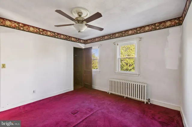 an empty room with windows and fan view