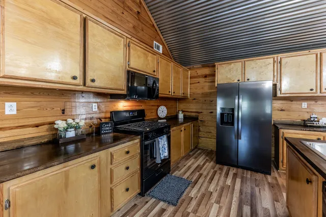a kitchen with stainless steel appliances granite countertop a sink a stove and a wooden floor