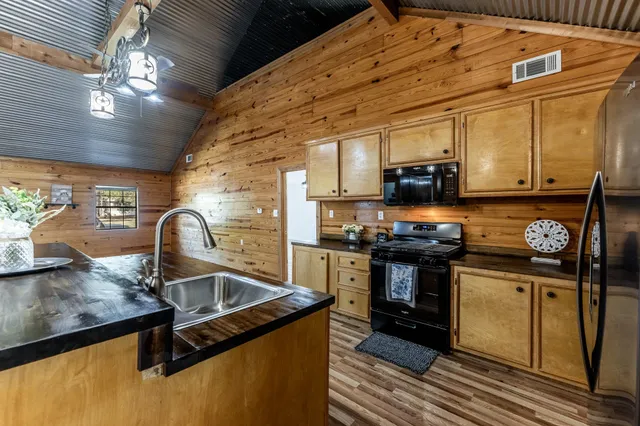an empty room with wooden floor chandelier and windows
