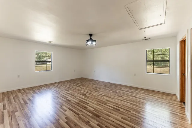 an empty room with wooden floor closet and windows