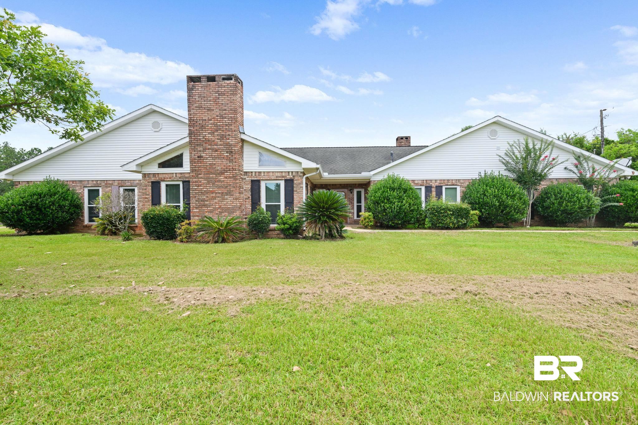 7540 2 Mile Road Irvington, AL 36544 - Photo 1 of 82 Brick exterior home featuring a prominent central chimney, white siding gables, and dark shutters