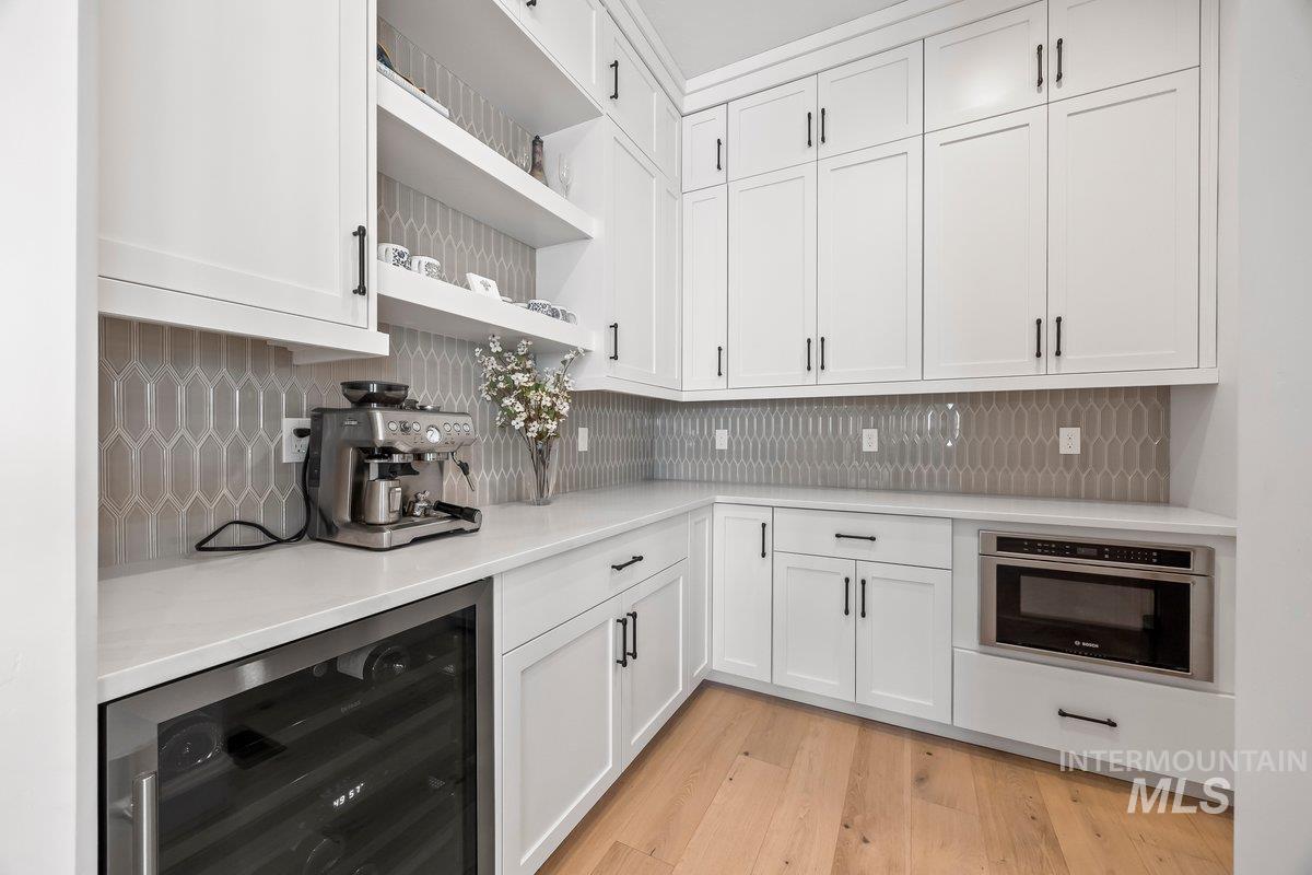 13746 North Ruffed Grouse Way Boise, ID 83714 - Photo 11 of 43 Kitchen featuring beverage cooler, light countertops, white cabinetry, open shelves, and decorative backsplash