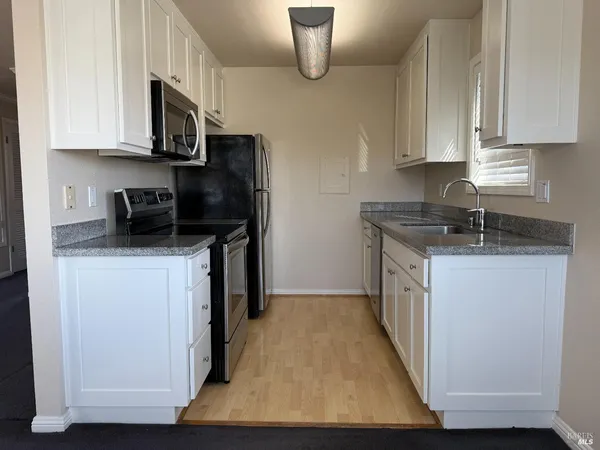 a kitchen with stainless steel appliances granite countertop a stove a sink and a white cabinets