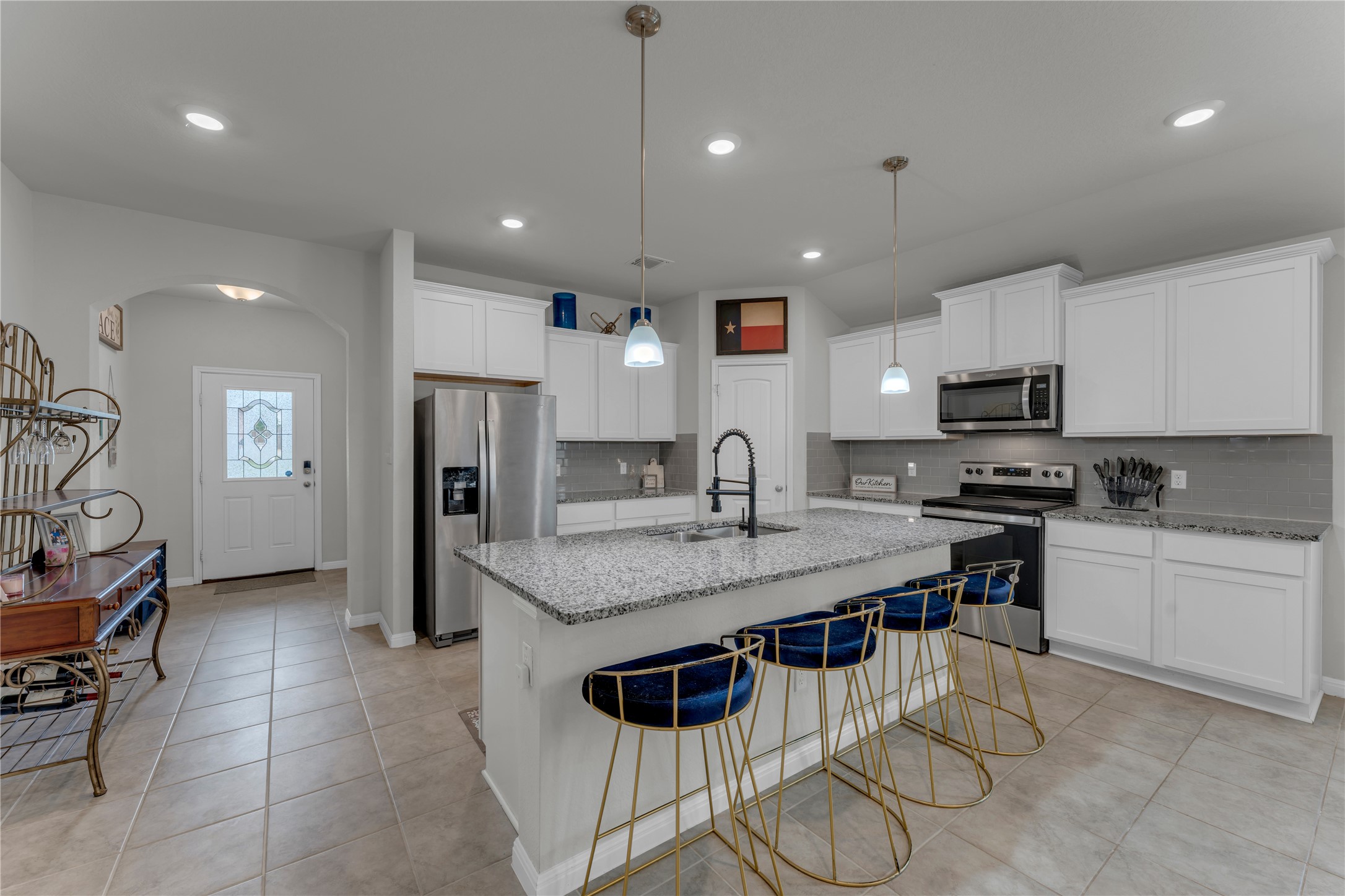 132 Cinnamon Loop Burnet, TX 78611 - Photo 5 of 27 Modern kitchen featuring a large island with pendant lighting, stone countertops, stainless steel appliances, white cabinetry, and tile flooring