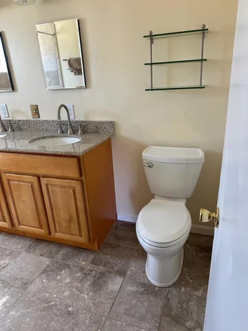 a view of an empty room with wooden floor and a ceiling fan