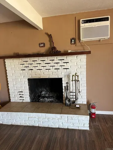 a view of an empty room with wooden floor fireplace and a window
