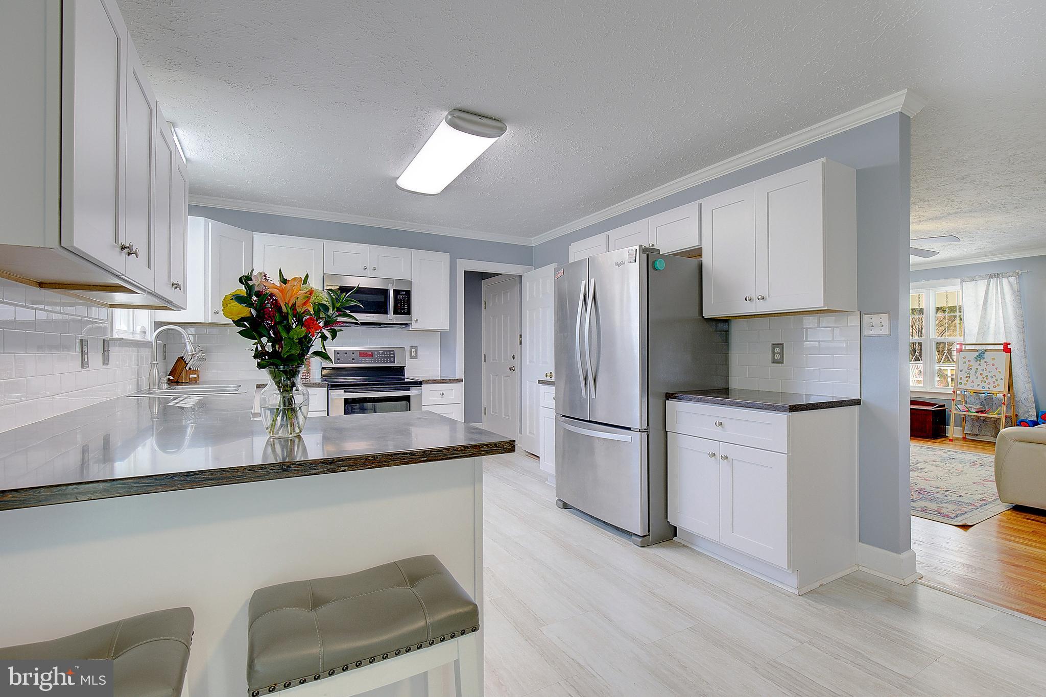 26282 Rio Bravo Lane Mechanicsville, MD 20659 - Photo 13 of 52 a kitchen with stainless steel appliances granite countertop a refrigerator a sink dishwasher and white cabinets with wooden floor