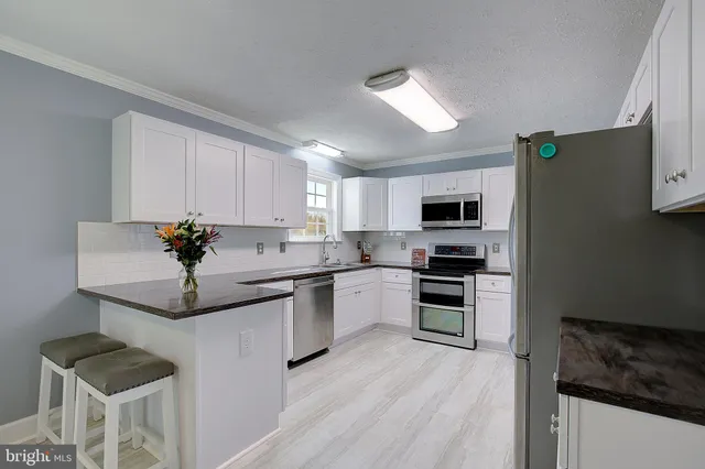 a kitchen with granite countertop stainless steel appliances and white cabinets