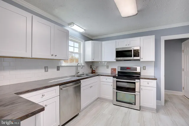 a kitchen with white cabinets stainless steel appliances and a sink
