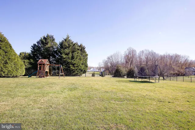 a front view of a house with a yard and a large tree