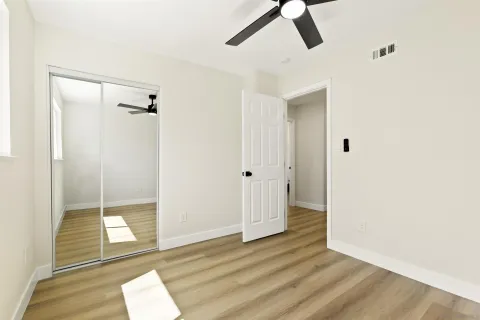 a view of empty room with wooden floor and fan