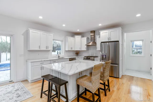 a kitchen with stainless steel appliances granite countertop a table chairs sink refrigerator and cabinets
