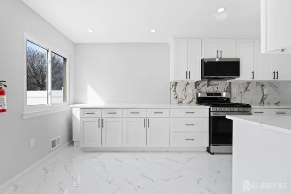 a kitchen with white cabinets and black stainless steel appliances