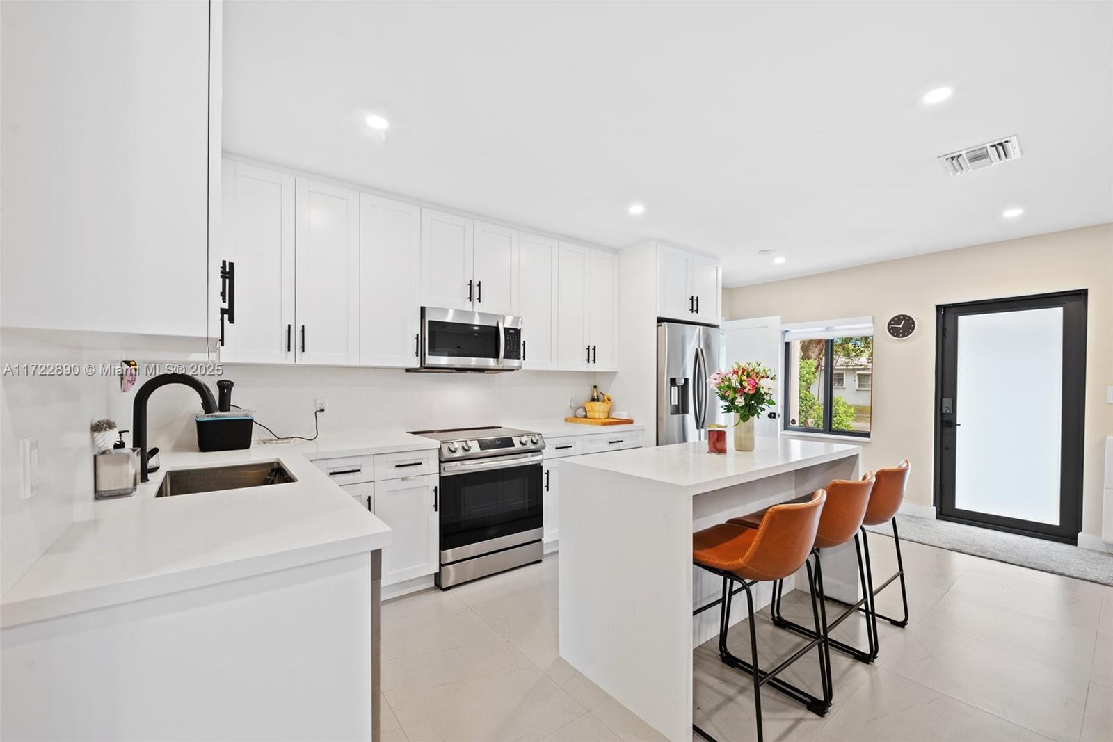 620 Cardinal Street Miami Springs, FL 33166 - Photo 7 of 24 a kitchen with stainless steel appliances a stove a sink a refrigerator and white cabinets with wooden floor