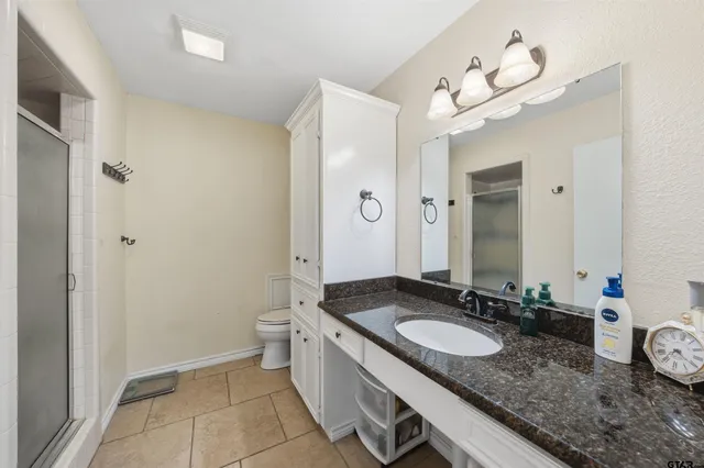 a bathroom with a granite countertop sink a toilet and a mirror