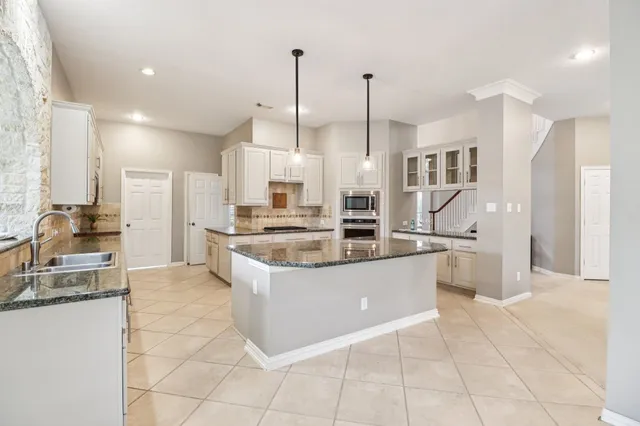 a kitchen with stainless steel appliances granite countertop a stove a sink and white cabinets