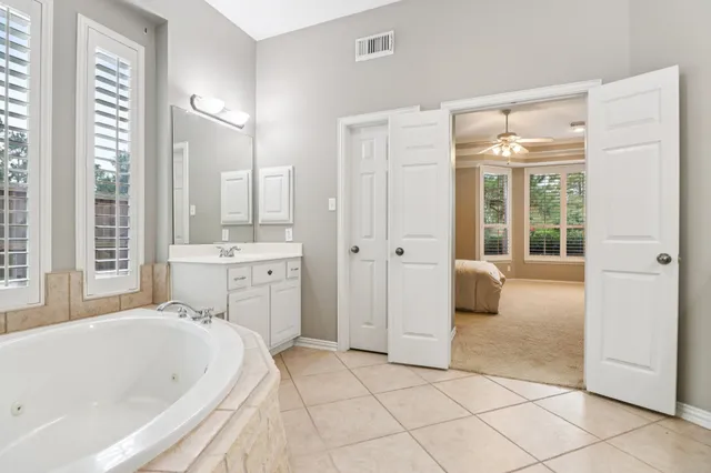 a bathroom with a white bath tub a sink and a mirror