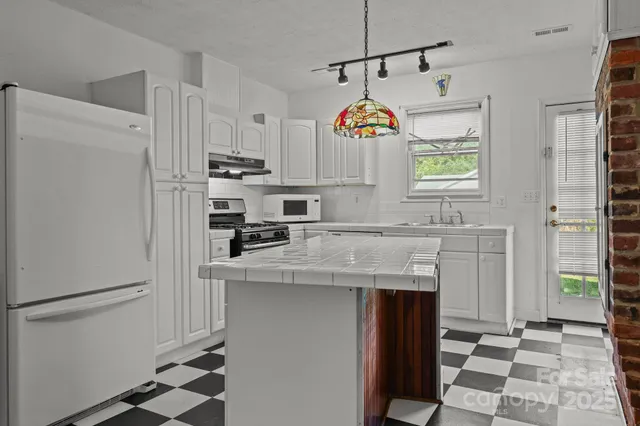 a kitchen with granite countertop white cabinets and appliances