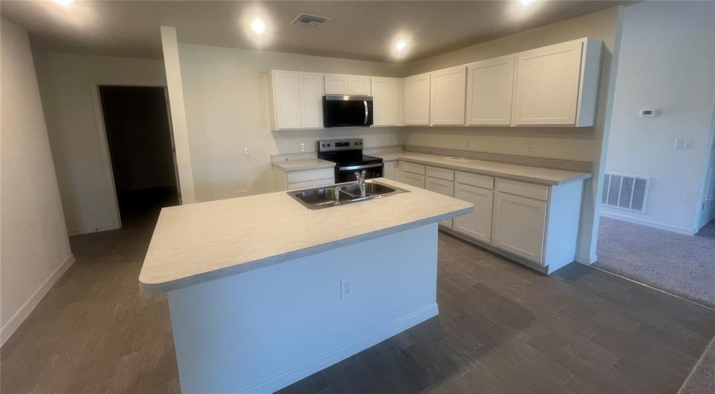 1436 Pulaski Street Port Charlotte, FL 33952 - Photo 2 of 3 a kitchen with kitchen island white cabinets and refrigerator