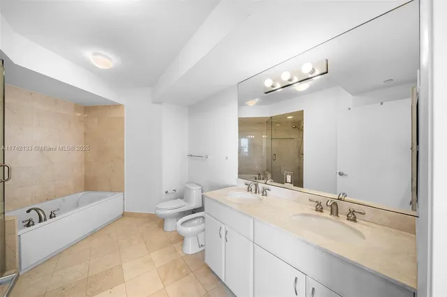 a bathroom with a double vanity sink toilet mirror and bathtub