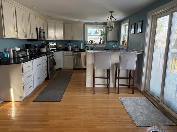 a kitchen with stainless steel appliances granite countertop a stove top oven a sink a dining table and chairs