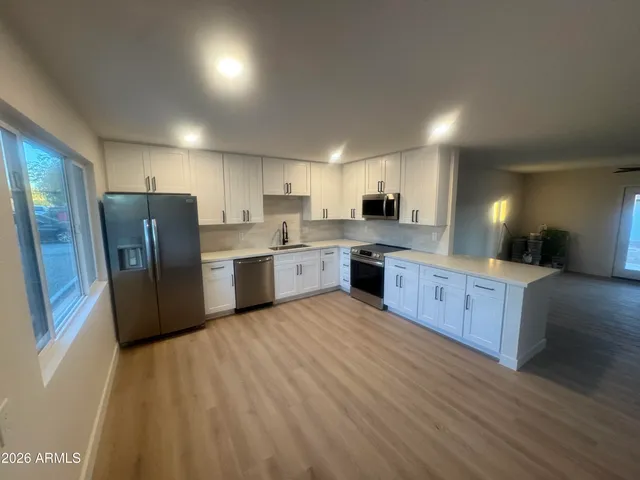 a kitchen with stainless steel appliances granite countertop a refrigerator a sink dishwasher a stove with wooden cabinets and wooden floor