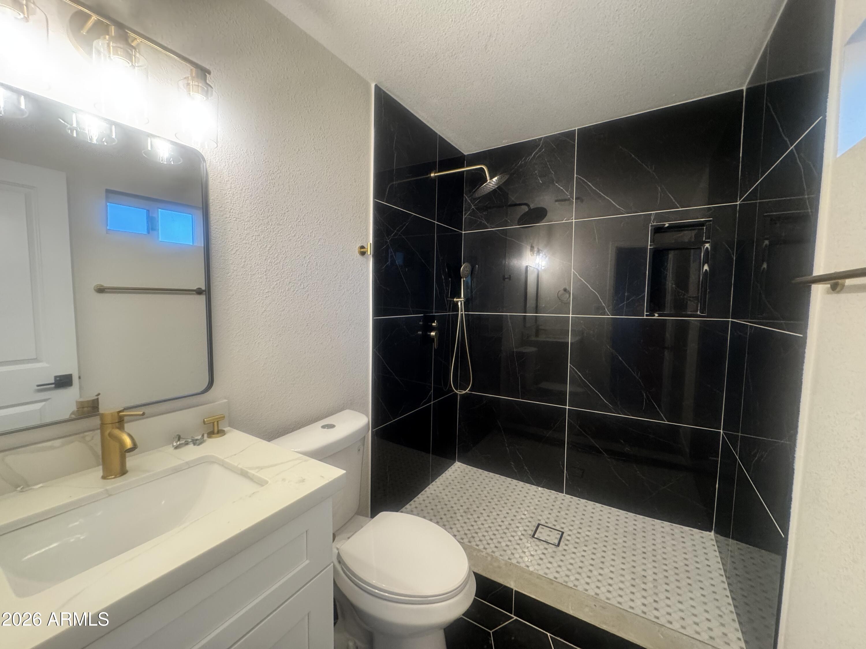 3337 West Ocotillo Road Phoenix, AZ 85017 - Photo 16 of 22 a bathroom with a sink a toilet a mirror and shower