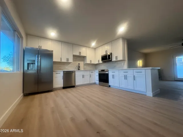 a large kitchen with stainless steel appliances granite countertop a stove a sink and a refrigerator